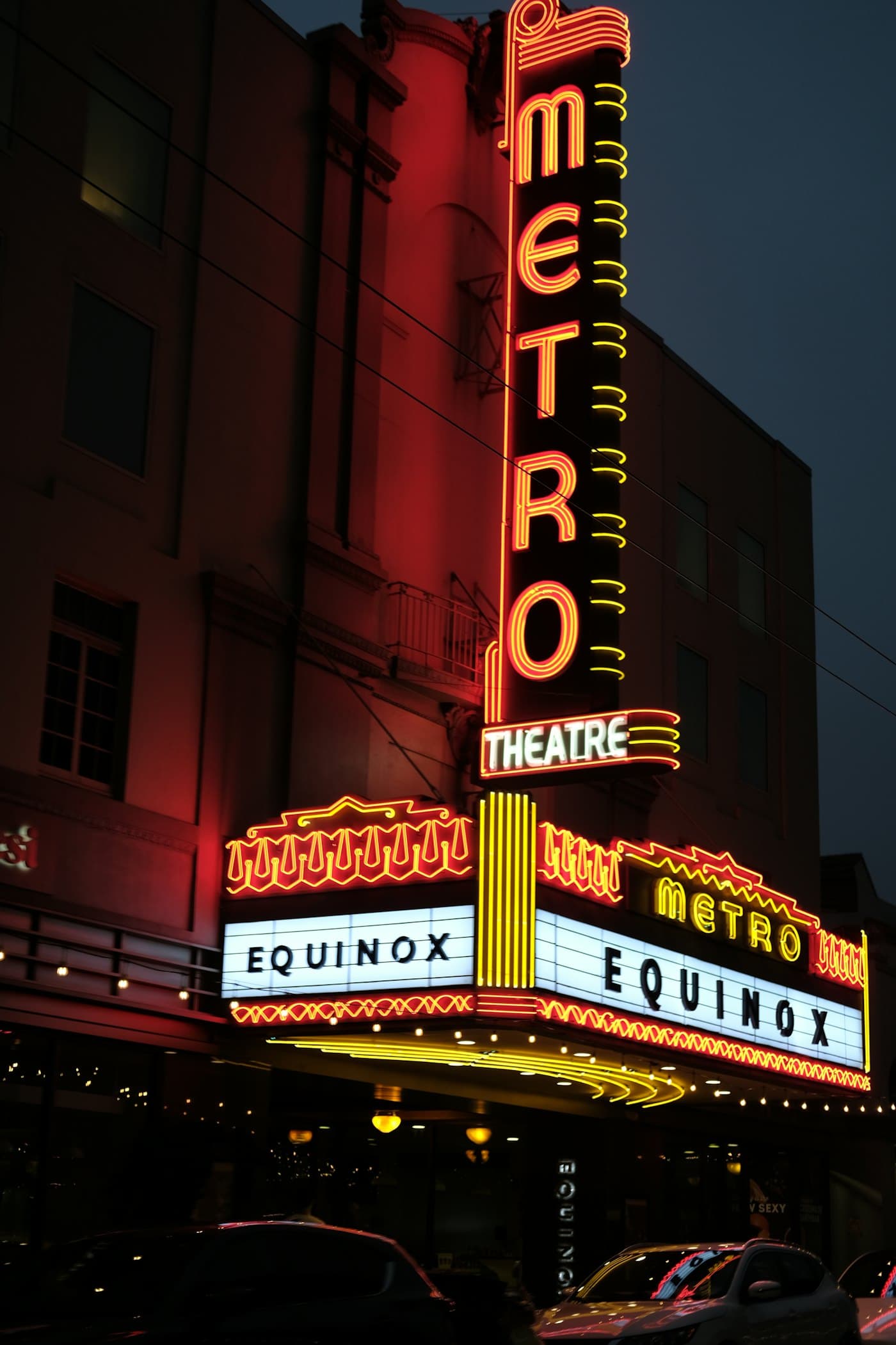 A theatre marquee lit in red and gold at night